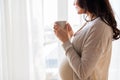 Close up of pregnant woman with tea cup at window Royalty Free Stock Photo