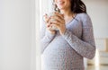 Close up of pregnant woman with tea cup at window Royalty Free Stock Photo