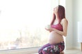 Pregnant woman with tea cup at window Royalty Free Stock Photo