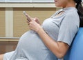 Close up pregnant woman texting with a smartphone Royalty Free Stock Photo