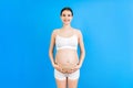 Close up of pregnant woman in underwear wearing elastic pregnancy bandage to make the pain go away at yellow background with copy Royalty Free Stock Photo