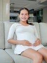 Close up pregnant women sitting at the sofa and touching her tummy Royalty Free Stock Photo