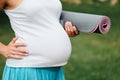 Close-up pregnant yoga woman with mat portrait in park on the grass, breathing, stretching, statics. outdoor, forest. Royalty Free Stock Photo