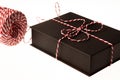 Close-up of present. Black box, resent packaging paper with red and white stripes and striped cord.