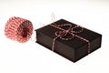 Close-up of present. Black box, resent packaging paper with red and white stripes and striped cord.