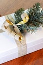 Close-up of present on a wooden vintage table. White gift box with golden bow and branch of Christmas tree. Royalty Free Stock Photo