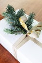 Close-up of present on a wooden vintage table. White gift box with golden bow and branch of Christmas tree. Royalty Free Stock Photo