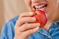 Close-up of a pretty Caucasian woman with her mouth open holding a red apple in her hand. Front three-quarter view from a low Royalty Free Stock Photo