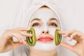 Close up of pretty smiling woman with white moisturizing mask and pieces of fresh kiwi fruit on cheeks. Beauty facial Royalty Free Stock Photo