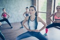 Close up of a pretty sporty lady, training. Five young slim ladies are stretching their legs and arms by doing squat exercise, we Royalty Free Stock Photo