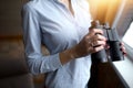 Close-up. Pretty woman holding the binoculars and admiring the local landscape. The evening sun shines in the window Royalty Free Stock Photo