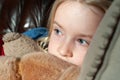 Close up of pretty young blonde girl`s eyes while cuddling her teddy