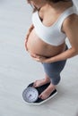 Pretty young pregnant woman standing on scales at home Royalty Free Stock Photo