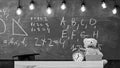 Close up of primary school classroom. Classroom with chalkboard on background. Childish desk with alarm clock and teddy