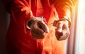 Close up of prisoner`s hands with handcuffs in orange jumpsuit at prison