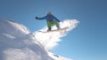 CLOSE UP: Pro snowboarder jumping in fresh snow, spraying snowflakes over sun