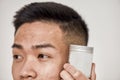 Close up of problematic skin of young asian man holding cream jar isolated over white background. Beauty, skincare Royalty Free Stock Photo