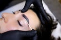 Close-up of the procedure of coloring the eyebrows with paint is performed after the procedure of lamination of the eyebrows