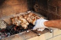 Close-up on the process of cooking barbecue of pork or beef meat mounted on skewers in a grill with a crispy burnt crust over gray Royalty Free Stock Photo