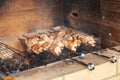 Close-up on the process of cooking barbecue of pork or beef meat mounted on skewers in a grill with a crispy burnt crust over gray Royalty Free Stock Photo