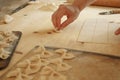 Close up process of homemade vegan farfalle pasta with durum wheat flour. The cook shapes the dough on the wooden cutting board,