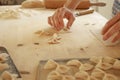 Close up process of homemade vegan farfalle pasta with durum wheat flour. The cook shapes the dough on the wooden cutting board,