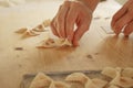 Close up process of homemade vegan farfalle pasta with durum wheat flour. The cook shapes the dough on the wooden cutting board,