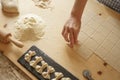 Close up process of homemade vegan farfalle pasta with durum wheat flour. The cook shapes the dough on the wooden cutting board,