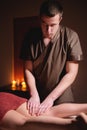 Close-up professional calf muscle massage to a female client by a male physiotherapist in a massage parlor in a dark