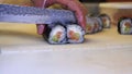 Close-up of professional chef`s hands in transparent gloves making sushi and rolls in a restaurant kitchen. Japanese traditional f Royalty Free Stock Photo