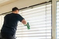 Professional cleaner deep cleaning window blinds in an apartment with a green microfiber cloth Royalty Free Stock Photo