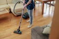 CLose up of professional Cleaning lady wearing uniform vacuums floor in living room