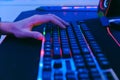 Close-up of professional esports player\'s hand and push mechanical keyboard with neon light on the large mouse pad.