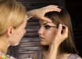 Close-up of professional make-up artist applying eyeliner on eyelid. Stylist is doing make up for female by eyeliner Royalty Free Stock Photo