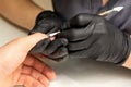 Close up professional manicurist master holding customer hand while using a cuticle pusher in a nail salon. Royalty Free Stock Photo