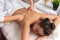 Close-up professional masseuse performing with hand back massage to young woman client in wellness spa center, beauty photo