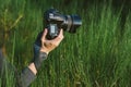 Close-up, professional photo-video camera in the hands of a girl. Against the background of green nature and forest Royalty Free Stock Photo