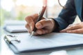 Close-up of a professional\'s hand signing an important document with a silver pen on a sunny day, signifying agreement and