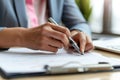 Close-up of a professional\'s hand signing an important document with a silver pen on a sunny day, signifying agreement and