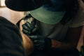 Close up of professional tattooer artist doing picture on hand of man by machine black ink from a jar Royalty Free Stock Photo
