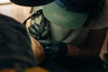 Close up of professional tattooer artist doing picture on hand of man by machine black ink from a jar Royalty Free Stock Photo