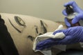 Close up professional woman tattooer cleaning tattoo in a man le Royalty Free Stock Photo