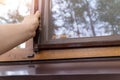 Close-up professional worker hand installing window mosquito insect fly screen protection at wooden house exterior wall