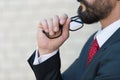 Close up profile of bearded businessman and hand holds glasses. Man in blue suit and red tie thinking over new idea. Royalty Free Stock Photo