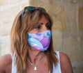 Close-up profile photograph of a beautiful, mature woman with a colorful printed mask