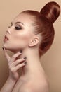 Close up profile portrait of beautiful red-haired model with her hair scraped back into a high bun