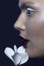 Close up profile portrait of a female model, with artistic makeup and flowers near face, isolated on a black background. Royalty Free Stock Photo