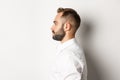 Close-up profile shot of handsome bearded man looking left, standing against white background Royalty Free Stock Photo