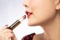 Close up profile view of young beautiful woman with red lips holding her Mutelu lipstick Royalty Free Stock Photo