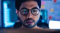 Close-up of a programmer intensely focused on his work, with computer code reflecting in his glasses